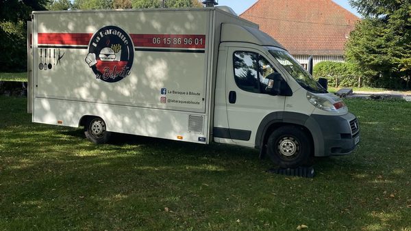 Le camion La Baraque à Biloute garé sur la place du village