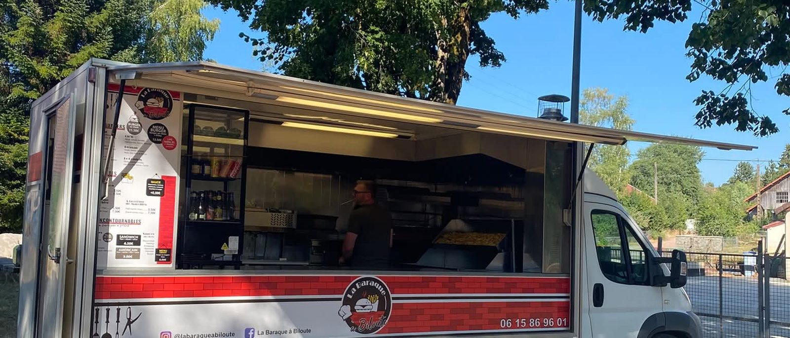 Le camion La Baraque à Biloute ouvert, en plein service sous les arbres